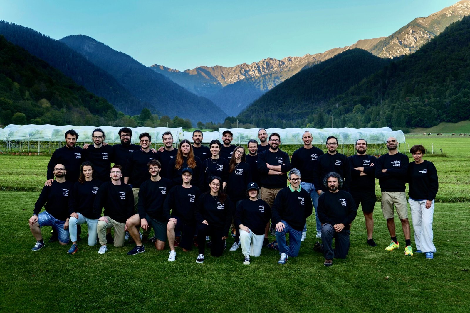 Foto aziendale Uqido con team su un prato e le montagne di sfondo